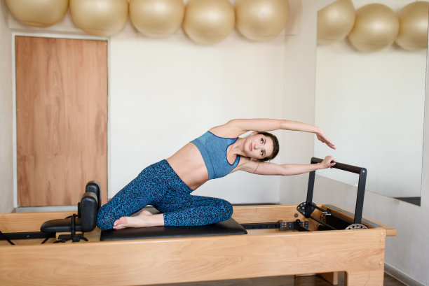 健身房里的女运动员在健身机上做弯腰练习。图片下载