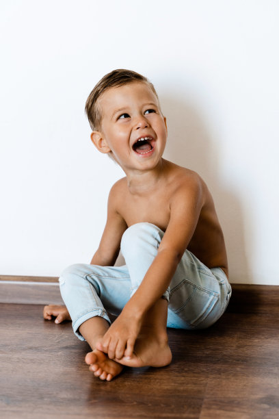 快乐开朗的小男孩穿着牛仔裤对着白墙摆姿势图片下载