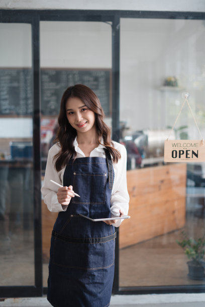 年轻的亚洲咖啡师咖啡馆当地老板拿着药片，在咖啡店里接受顾客的点单。图片下载