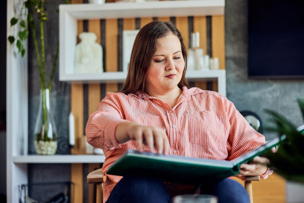 一个曲线优美的女人在家里看了一下午的家庭照片。图片下载