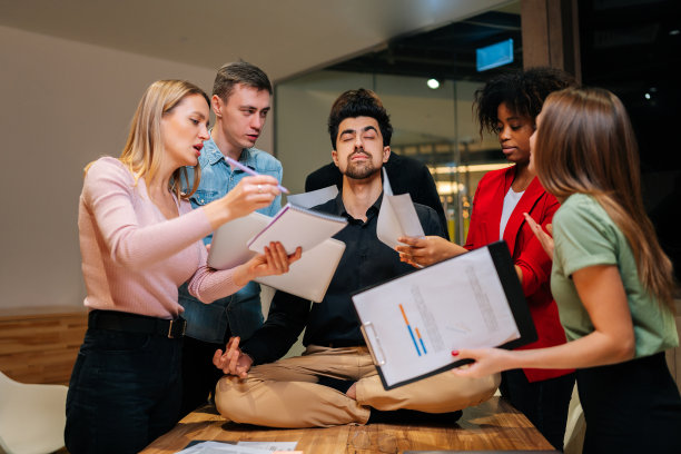 冷静的男性团队领导的肖像，以莲花的姿势坐在办公桌旁，闭着眼睛沉思，感觉平静和宁静。图片下载