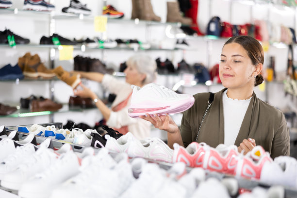 在多品牌皮具店，女孩选择现代舒适的跑步运动鞋健身图片下载