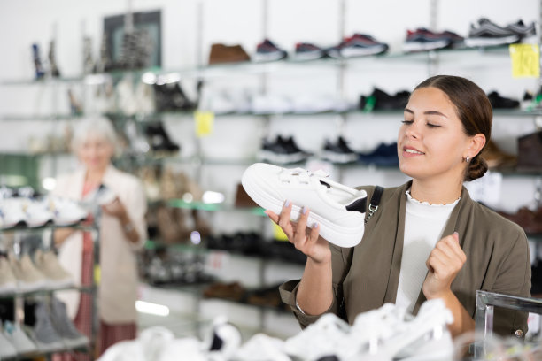 在多品牌皮具店，女孩选择现代舒适的跑步运动鞋健身图片下载