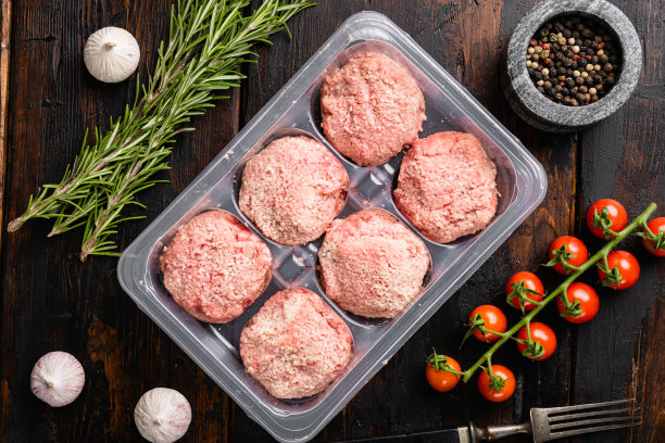 塑料包装的肉和肉丸，在旧的深色木桌背景上，俯视图平躺图片下载