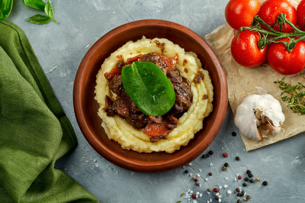 土豆泥和炖肉放在混凝土背景上的粘土盘子里图片下载