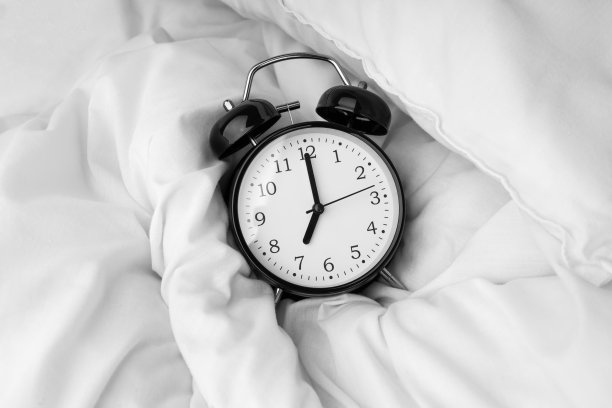 闹钟躺在白色的床上图片下载