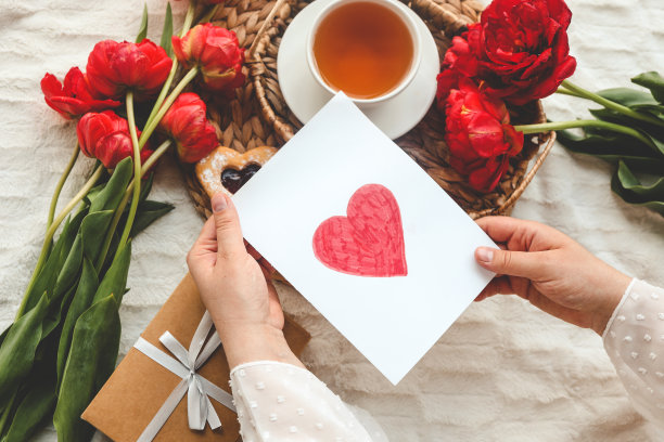 女人手里拿着一张精美的手绘母亲节贺卡，上面有红色的信封，卡片上有我爱你妈妈的字样图片下载
