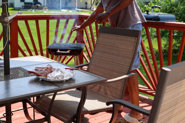 一个黑人把生肉放在木炭烤架上图片下载