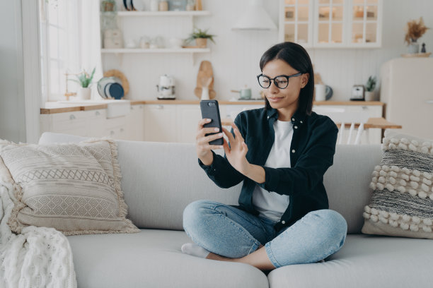 年轻的西班牙妇女有视频通话，放松，并通过手机上网冲浪。图片下载