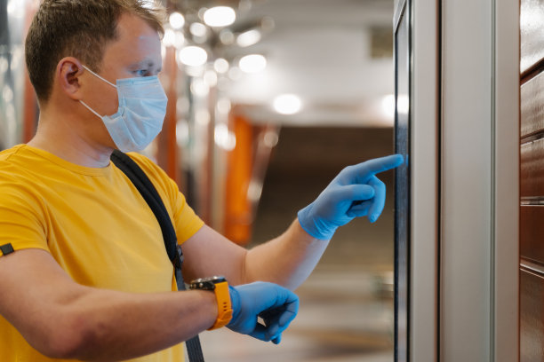 男子侧影查看手表上的时间，在防护橡胶手套上使用触摸屏，避免传播冠状病毒，大流行时间，戴医用口罩。卫生保健，检疫，病毒爆发图片下载