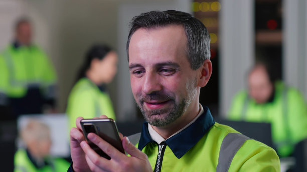 在办公室用智能手机拍摄穿着安全制服的工程师图片下载