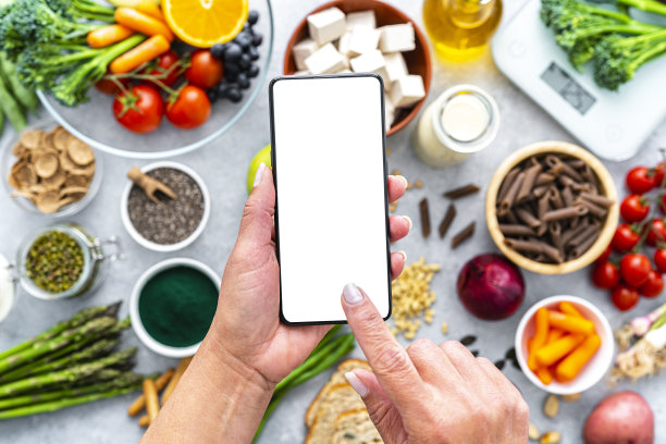 女子手持智能手机，屏幕为白色，背景为健康素食图片下载