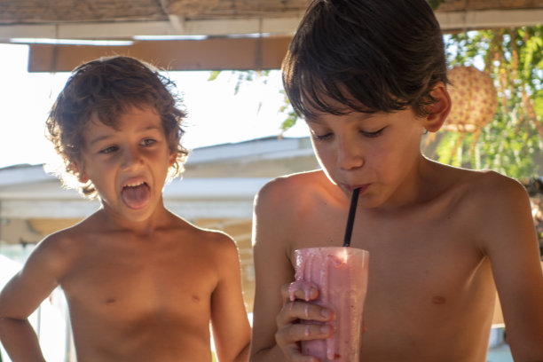 在沙滩上喝奶昔鸡尾酒的兄弟图片下载