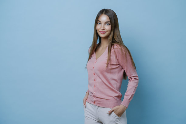 美丽时尚的理念。年轻迷人的女人自信而无忧无虑，穿着时髦的衣服，关心头发，孤立在蓝色的背景下，成功购物后的快乐图片下载