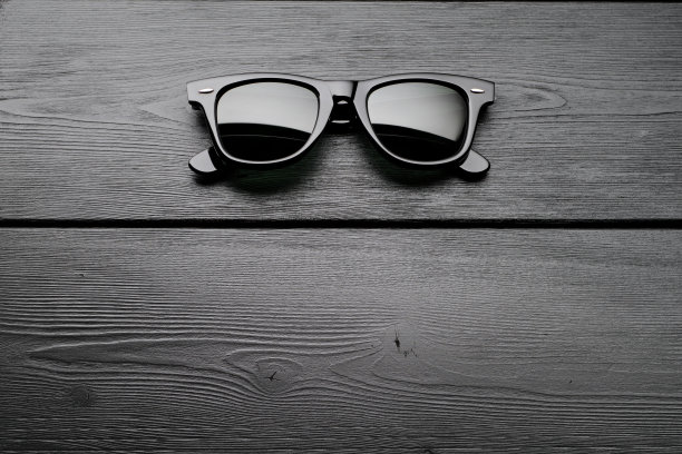 黑色塑料的经典太阳镜放在深色木桌上。俯视图，复制空间。图片下载