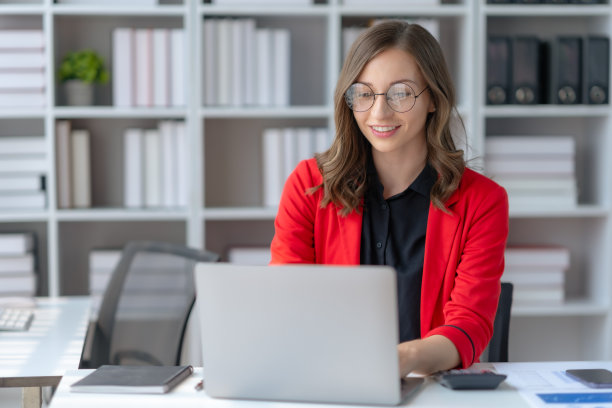 迷人的女商人坐在办公室的笔记本电脑上工作。图片下载