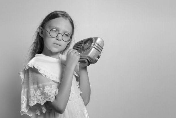 拿着过去收音机的女孩。听复古收音机。米色背景。古董图片下载