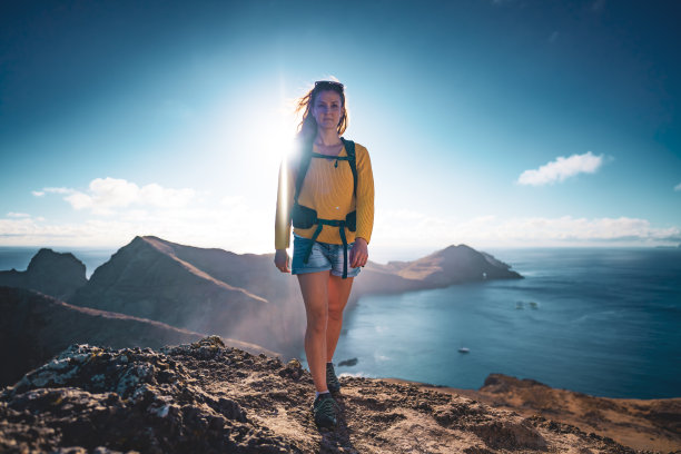 清晨，一名女性背包客在大西洋一座岛屿的山麓上行走的低角度正面照片。欧洲葡萄牙马德拉岛的<s:1> o loureno。图片下载