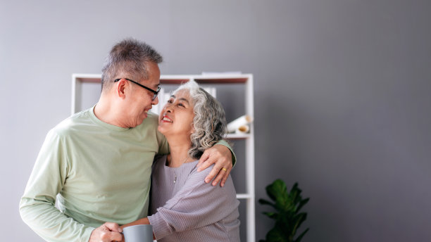 老夫妇在家里的客厅里喝着咖啡，拥抱着爱，花时间做一些放松生活的活动图片下载