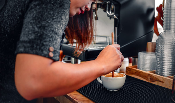 制作咖啡的咖啡师，用木勺制作或准备咖啡泡沫的手。图片下载