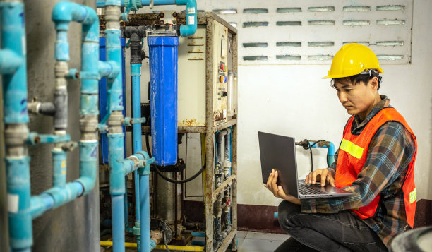 在水厂工作的工程师使用平板电脑检查水厂的水管理系统和锅炉水管图片下载