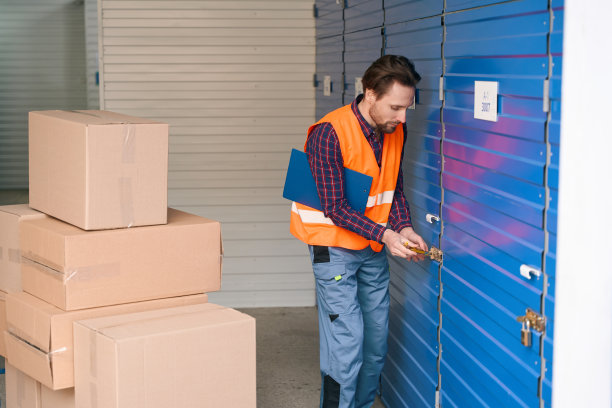 穿着工作服的年轻人带着大纸板箱进了仓库图片下载