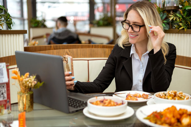 午餐时看手机和笔记本电脑的女商人图片下载