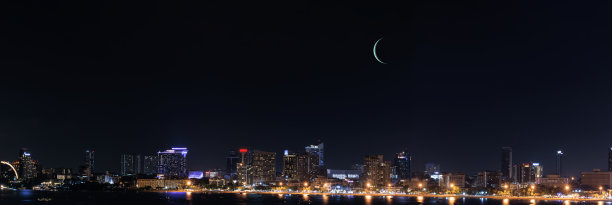 在泰国芭堤雅，摩天大楼在朦胧的蓝天、月亮和午夜时分。芭堤雅市以海上运动、旅游和夜生活娱乐而闻名。网页横幅的全景和复制空间。图片下载