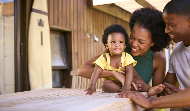 父母和小女儿坐在户外的桌子上玩耍的家庭照片图片下载