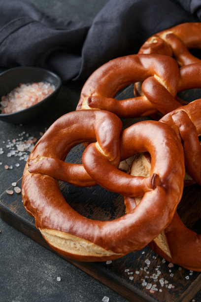 啤酒节概念卡。传统的巴伐利亚椒盐脆饼与啤酒瓶杯在古老的黑色乡村背景。非常适合十月节。啤酒节食物菜单。图片下载