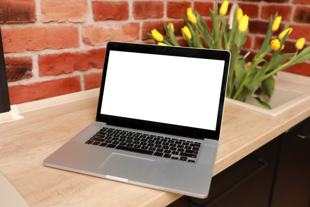 商业，自由职业者，博客的概念。在家庭办公室里，木桌上的笔记本电脑上有空白的白色屏幕，砖墙旁，花瓶里插着黄色的郁金香。模拟，复制空间。社交媒体，网站模板图片下载