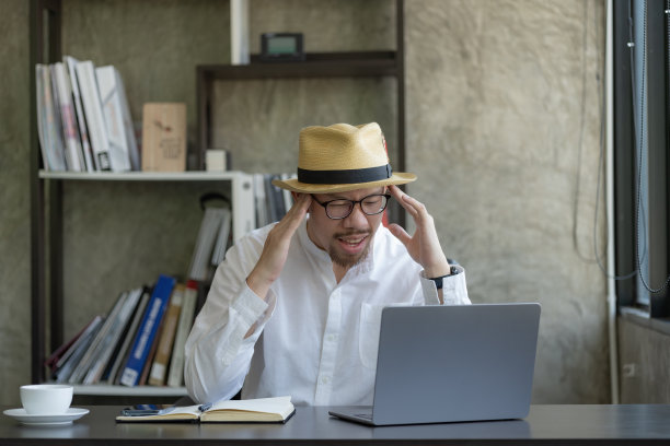 亚洲商人戴着帽子，在办公室里认真思考解决项目中的问题。图片下载