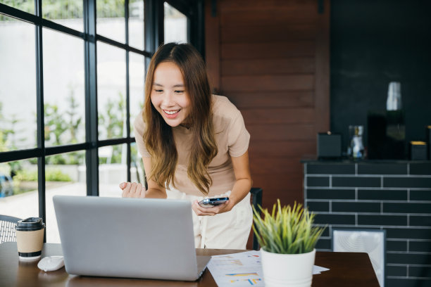 兴奋的女子手持智能手机，在玩完网络游戏后举起双手，做出获胜的手势图片下载