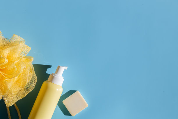 黄色的瓶子上有分配器、毛巾和蓝色的肥皂条。图片下载