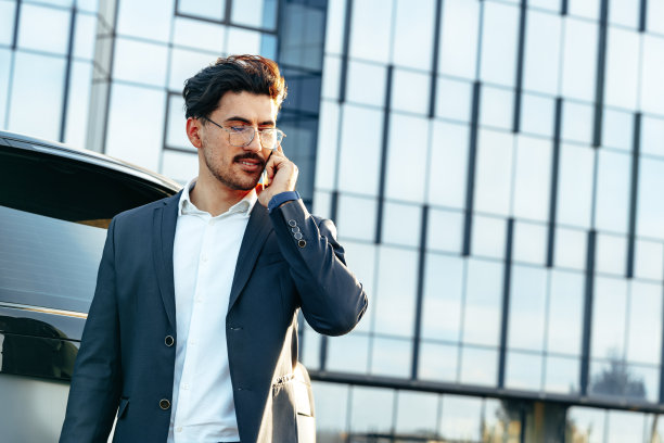 穿着正装的年轻商人站在豪车旁边讲电话图片下载