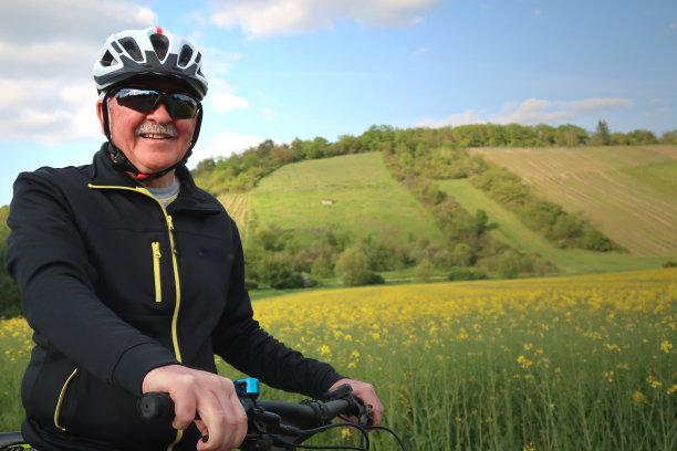老年人骑自行车在一个美好的日子/绿色景观风景图片下载