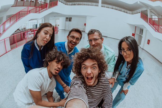 在一家现代医院的走廊里，一名医生和一名护士与一位坐轮椅的病人拍了一张自拍照，照片中洋溢着欢乐、包容以及科技对医疗保健的积极影响。图片下载