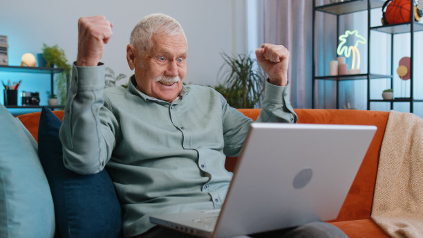 爷爷男人用笔记本电脑，接收好消息消息，为胜利而震惊，庆祝胜利图片下载