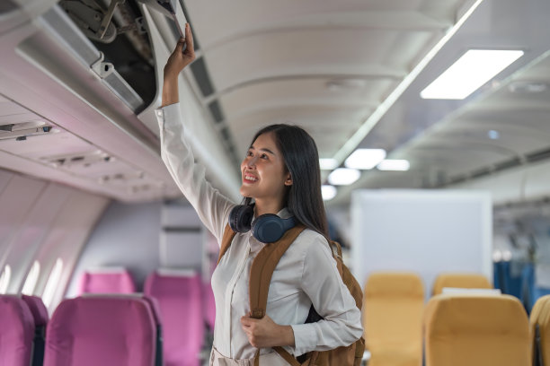 女人乘飞机旅行。鼓励乘客将手提行李放在飞机座位上方的储物柜中图片下载