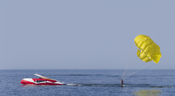 黄色的副帆翼在摩托艇的牵引下在水中滑行。图片下载