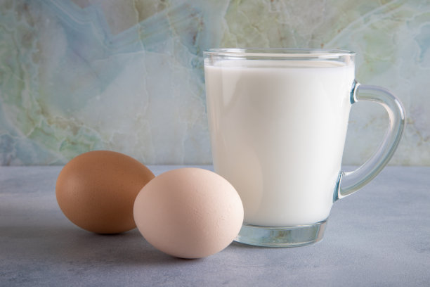 一杯牛奶和两个鸡蛋在蓝色的桌子上图片下载