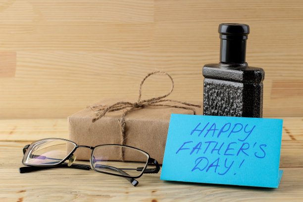 祝您父亲节快乐。文字和男士饰品，领带，香水和眼镜在一个自然的木制背景。图片下载