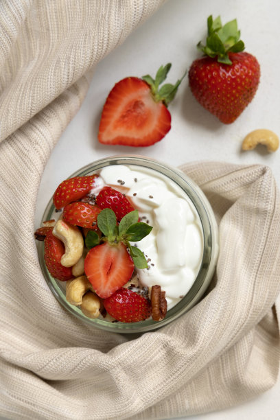 希腊酸奶、坚果和草莓装在玻璃罐里，放在白色的桌面视图上图片下载