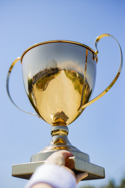 手捧金杯奖杯，迎着蓝天洒满阳光，胜利成功校队理念图片下载