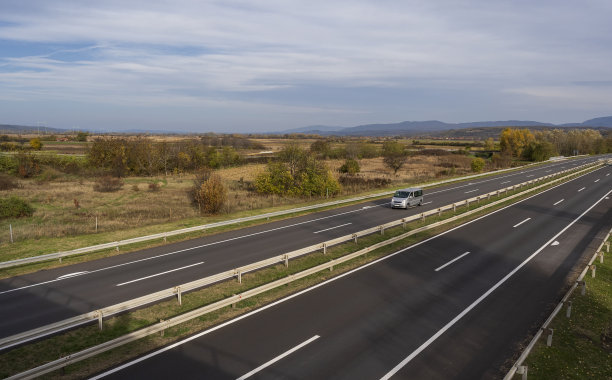 灰色现代快递小件货物快递车在高速公路上快速行驶到城市郊区。图片下载