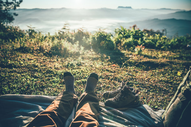 穿着袜子的旅行者腿。徒步旅行者欣赏外面的景色，早上在山上免费徒步旅行。旅行的概念。图片下载