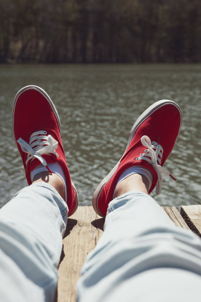 穿着红鞋的人在湖边的木甲板上放松。图片下载