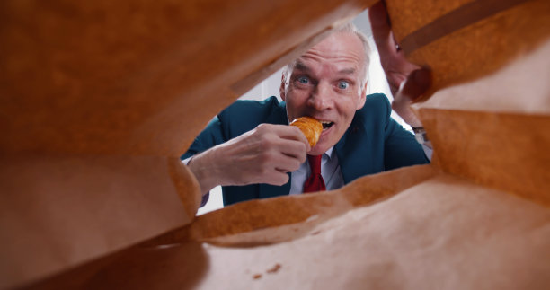 从带牛角包午餐的成熟商人纸袋里看一个工作场所图片下载