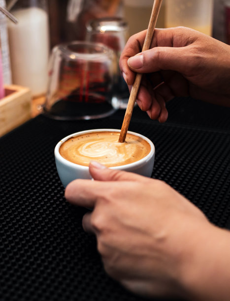 咖啡师用木勺制作或准备咖啡泡沫的特写镜头。咖啡师在煮咖啡图片下载