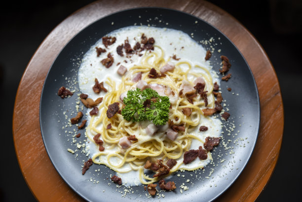 加培根的意大利面，放在深色碟子上。图片下载